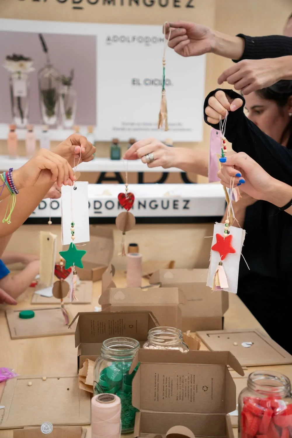 Varias manos muestran los adornos navideños terminados frente al espacio de Adolfo Domínguez